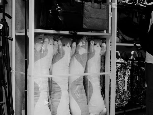 black and white photograph of a person standing in front of a rack of shoes