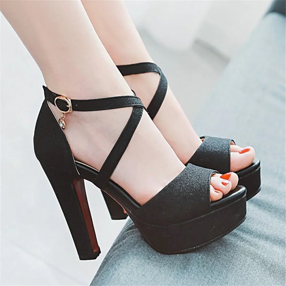 Black high-heeled platform sandals worn by a person on a light background