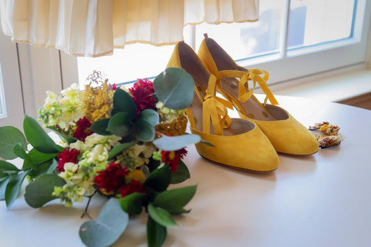 A pair of yellow high heeled shoes next to a bouquet of flowers