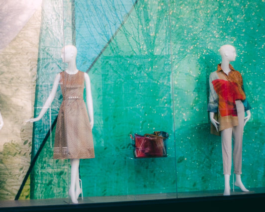 three mannequins in a window display with a green background