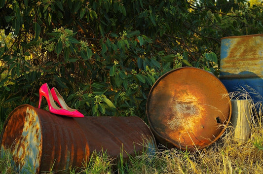 a pair of pink high heels sitting on top of a barrel