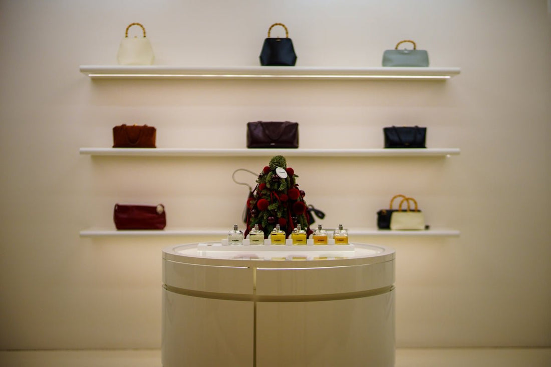 Designer handbags displayed on illuminated shelves above a display table.