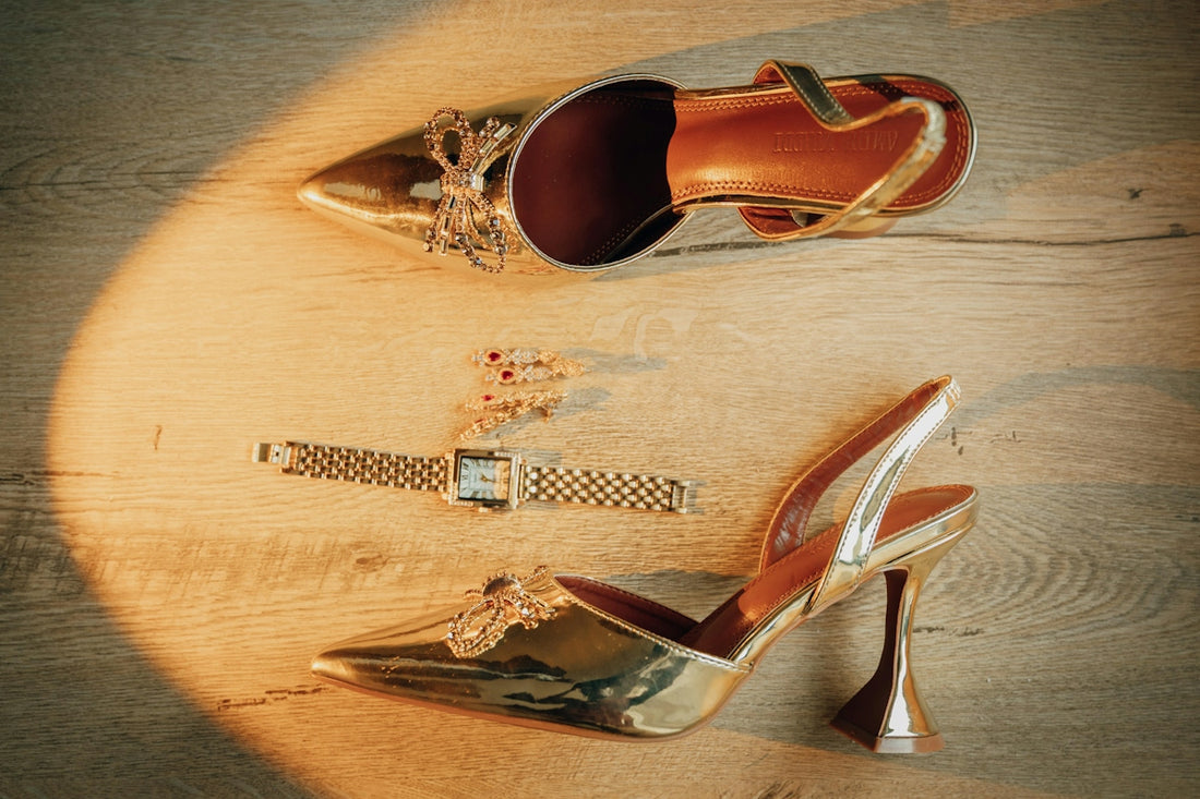 Golden high heels and a watch on a wooden floor