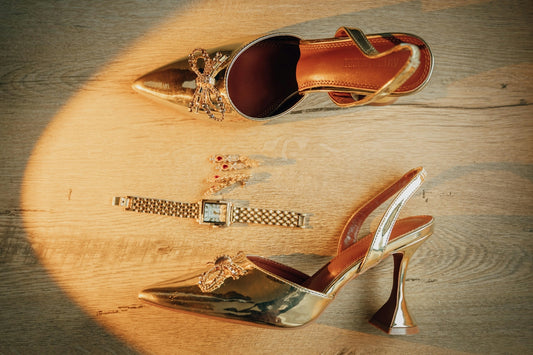 Golden high heels and a watch on a wooden floor