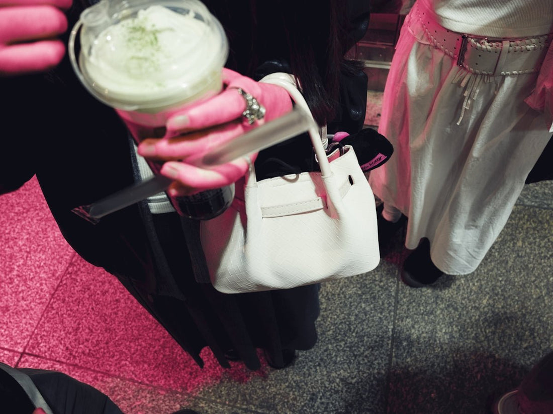 Person holding a drink and a white handbag