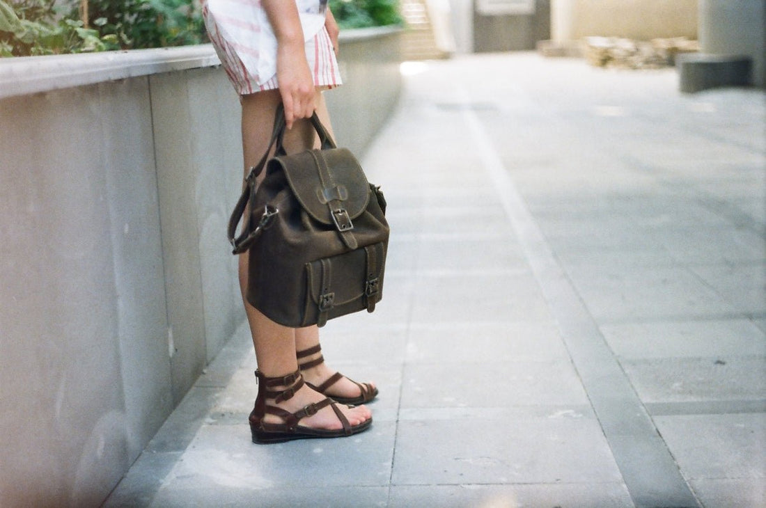 a woman standing on a sidewalk holding a purse