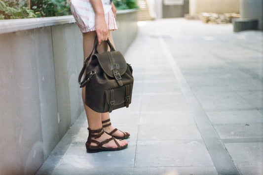 a woman standing on a sidewalk holding a purse