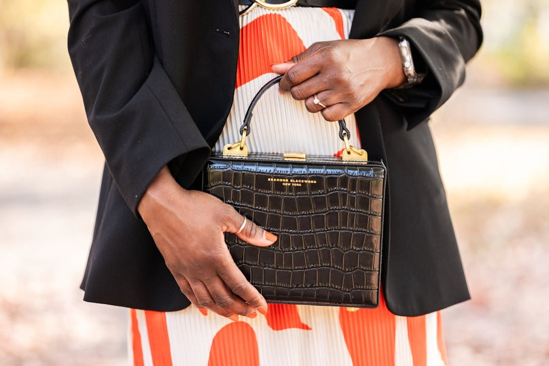 a woman in a dress holding a black purse