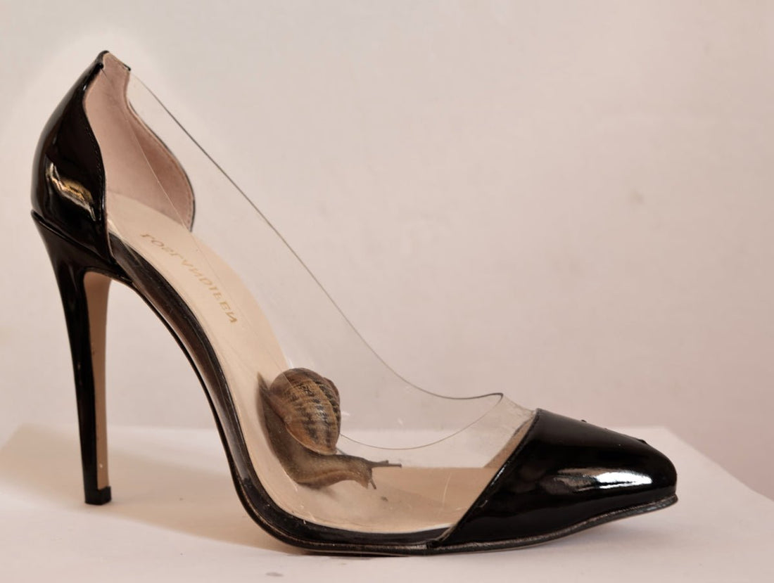 a pair of black high heels with a butterfly on the heel