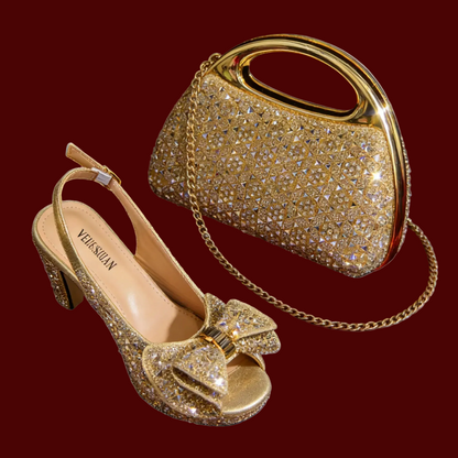 A gold rhinestone-embellished slingback high heel shoe and a matching handbag with a gold chain strap, shown on a plain maroon background.
