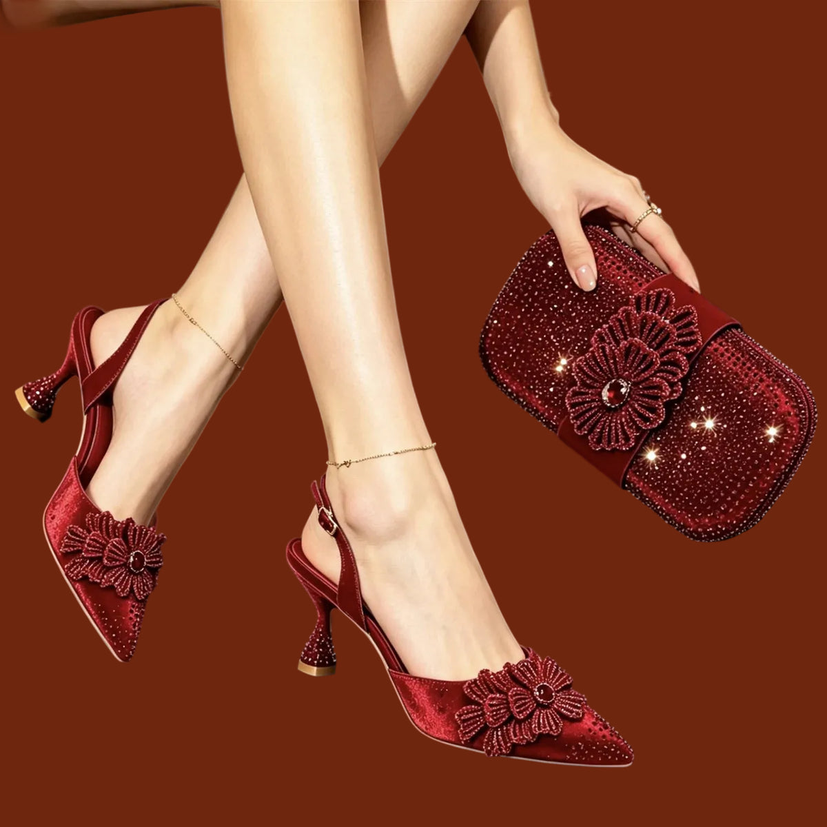 A person wearing deep red velvet slingback pointed-toe heels with large floral embellishments and holding a matching red beaded clutch bag against a dark brown background.