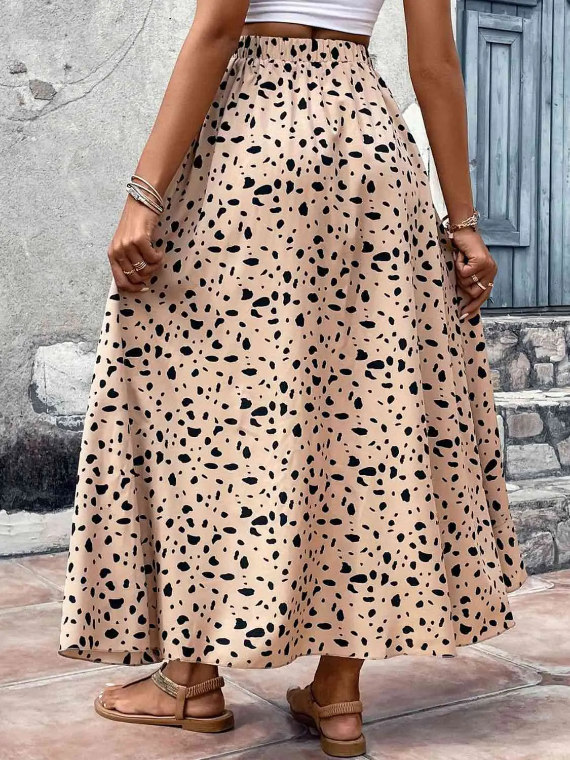 Person wearing a long, patterned skirt with a neutral background
