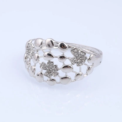 Silver ring with floral designs on a light gray background