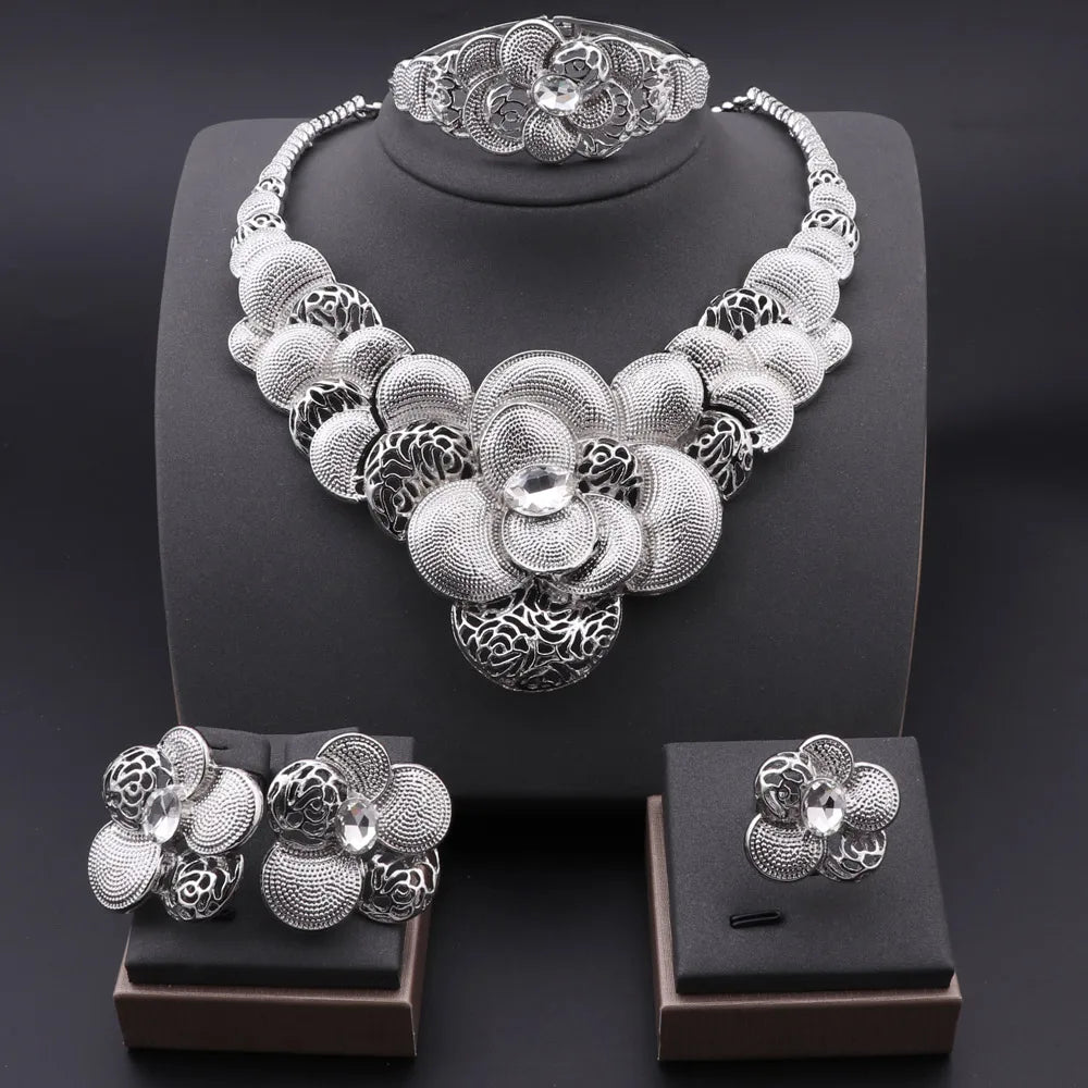 Silver floral jewelry set including necklace, bracelet, ring, and earrings on a dark background