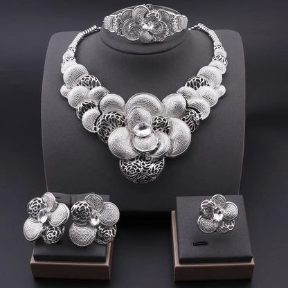 Silver floral jewelry set including necklace, bracelet, ring, and earrings on a dark background