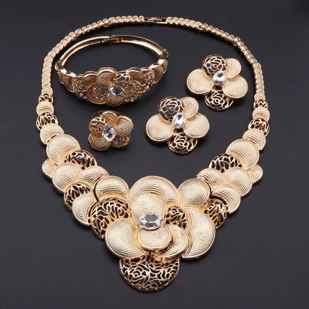 Gold necklace, bracelet, ring, and earrings set on a dark background