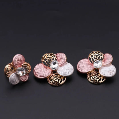 Two floral earrings and one floral ring with pink and gold colors on a black background