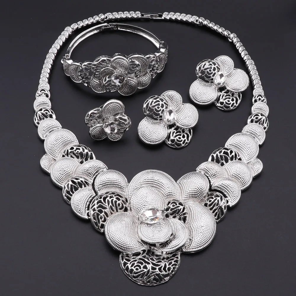 Silver floral jewelry set including necklace, bracelet, ring, and earrings on a dark background