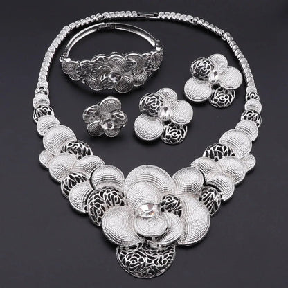 Silver floral jewelry set including necklace, bracelet, ring, and earrings on a dark background