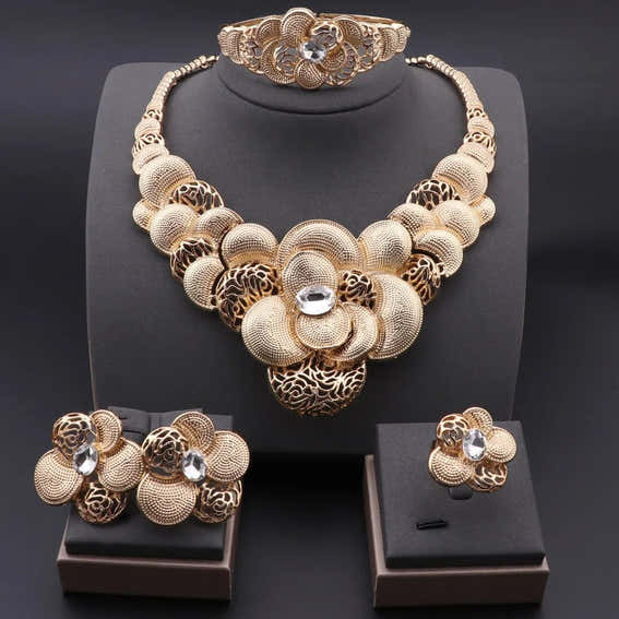 Gold necklace, bracelet, ring, and earrings set on a black background