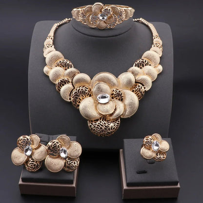 Gold necklace, bracelet, ring, and earrings set on a black background