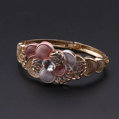 Decorative bracelet with floral designs and a central gemstone on a dark background