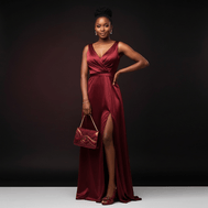 Woman in a burgundy evening gown, wearing wine elegant peep-toe heels and holding a matching handbag against a dark background