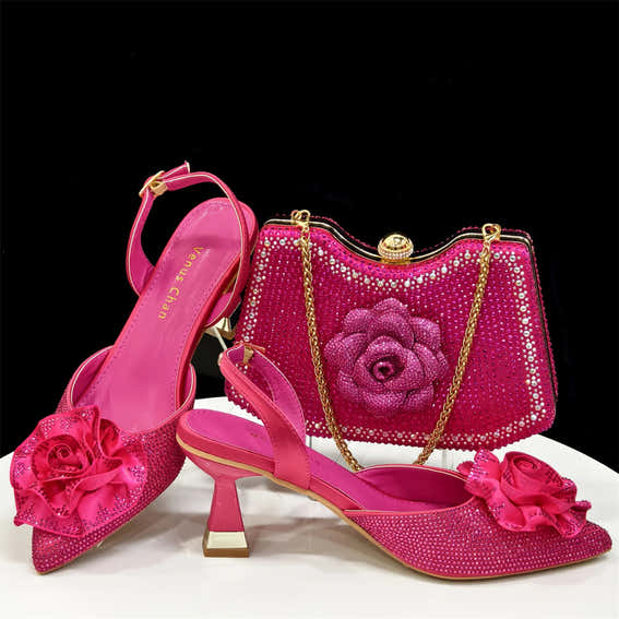 Fuchsia high-heeled shoes and matching handbag with floral design on a white surface.