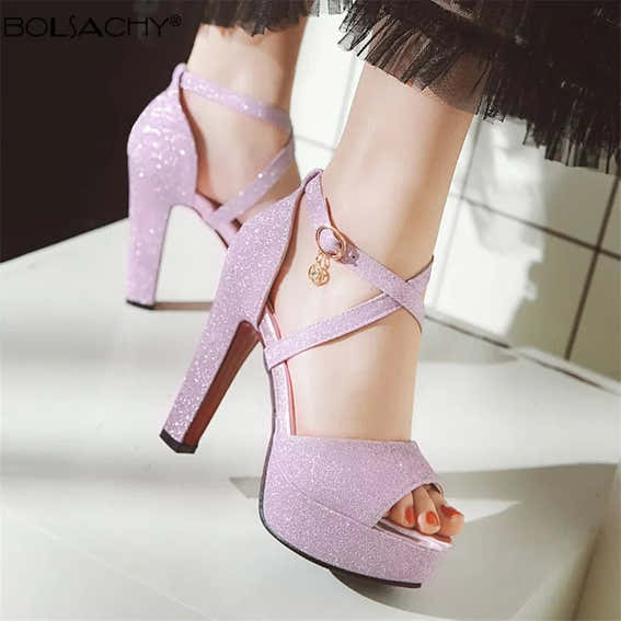 Purple glitter high-heeled shoes with a platform sole on a neutral background