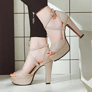 Gold glitter high-heeled shoes worn by a person on a tiled floor.