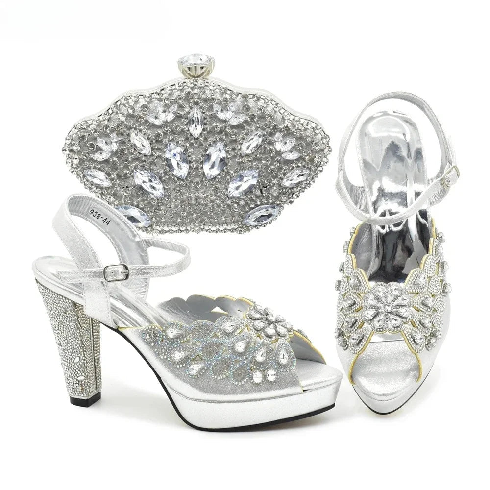Silver high-heeled shoes with detailed embellishments and a matching clutch on a white background