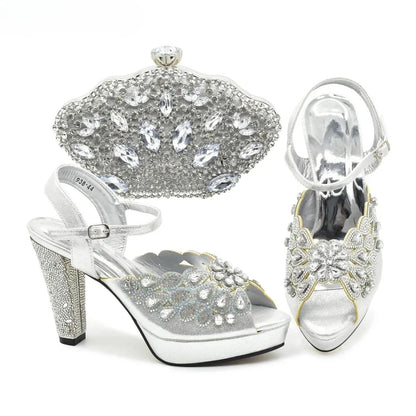 Silver high-heeled shoes with detailed embellishments and a matching clutch on a white background
