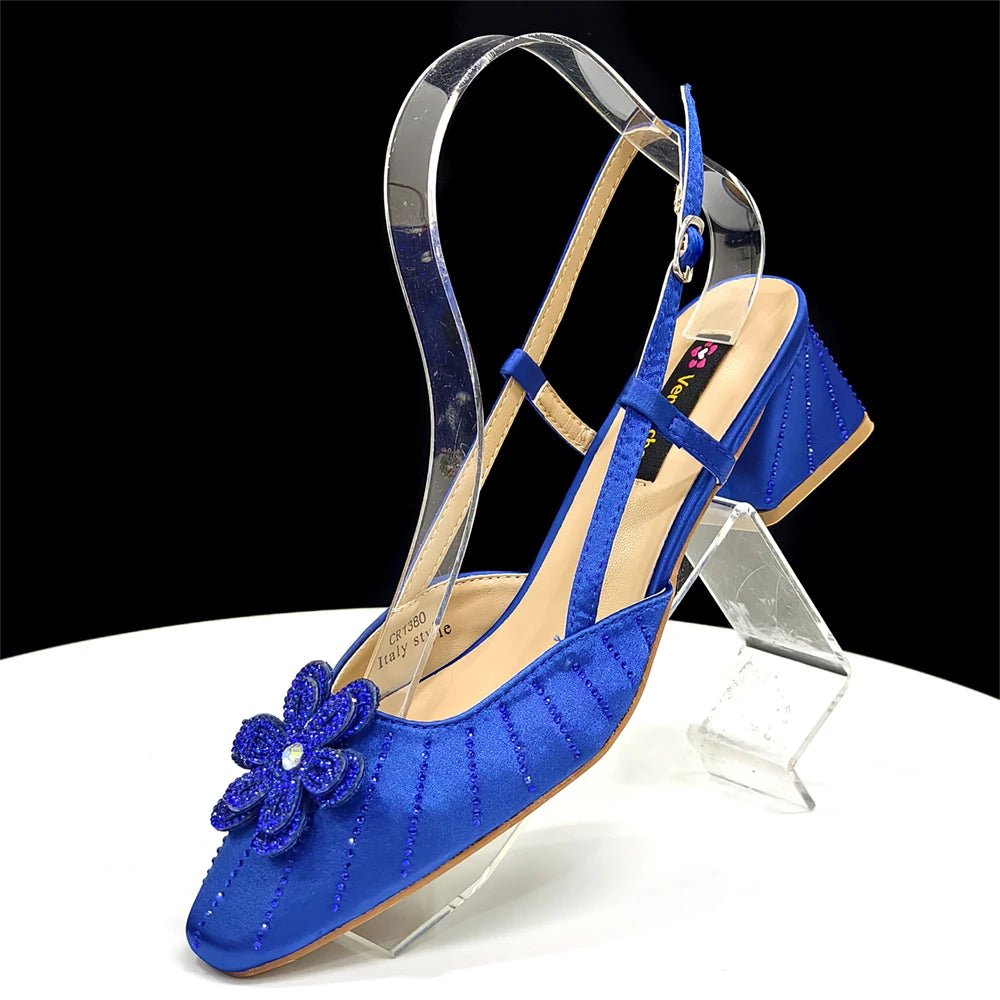 Blue Italian Rhinestone Heels with a flower detail | Elegant Wedding on a clear stand against a black background