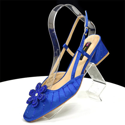 Blue Italian Rhinestone Heels with a flower detail | Elegant Wedding on a clear stand against a black background