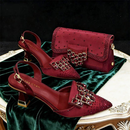 Wine high-heeled shoes and matching handbag on a green fabric background