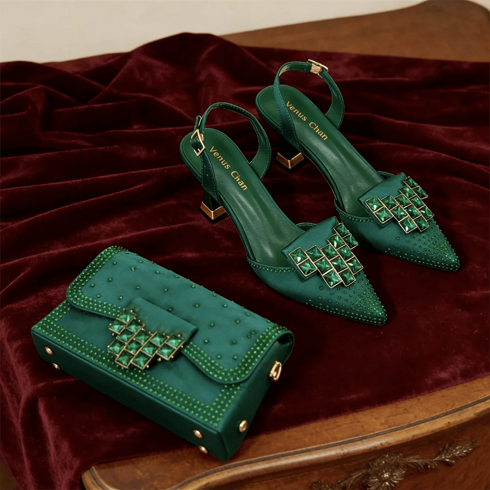 Green high-heeled shoes and matching handbag with rhinestone decor on a red fabric background
