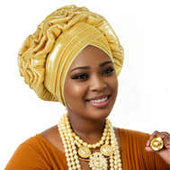 Woman wearing a gold Nigerian auto gele headwrap on a white background