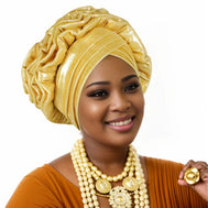 Woman wearing a gold Nigerian auto gele headwrap on a white background